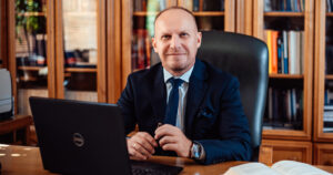 Dr. Mariusz Lekston nowy rektor siedzący w gabinecie przy biurku