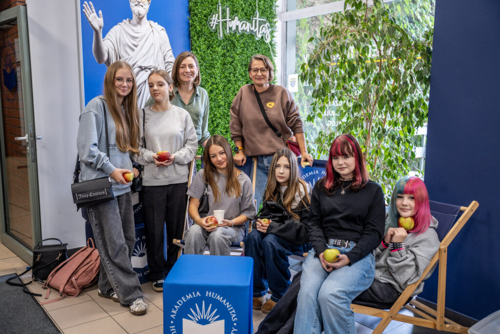 Grupa dziewcząt pozuje do zdjęcia na niebiesko-zielonym tle.