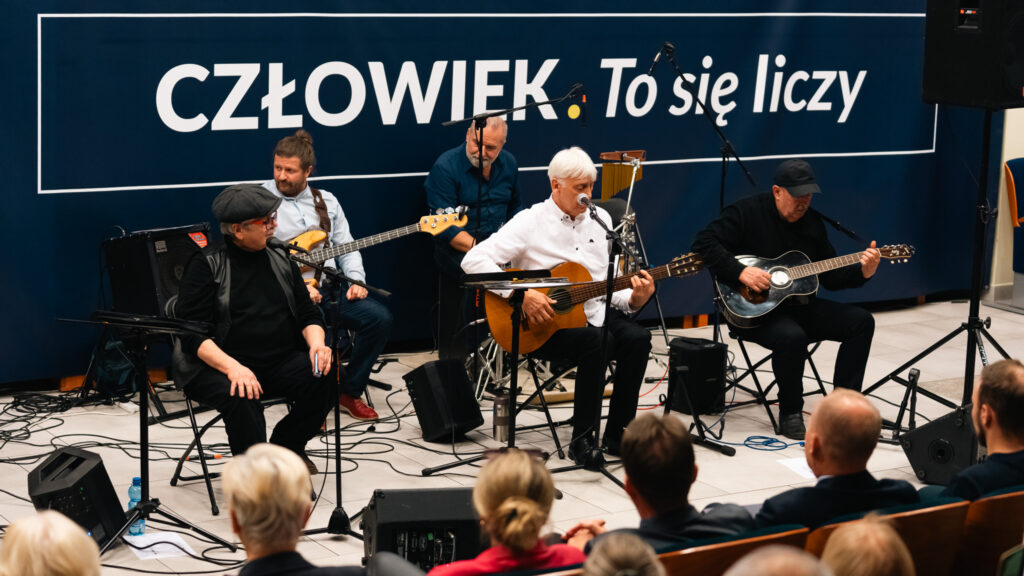Zespół muzyczny gra koncert podczas inauguracji w Akademii Humanitas na tle napisu „Człowiek. To się liczy.”