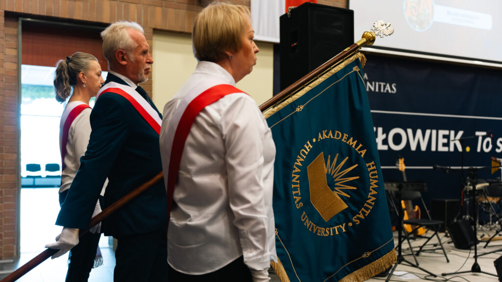 Poczet sztandarowy Akademii Humanitas podczas inauguracji roku akademickiego z widocznym sztandarem uczelni.