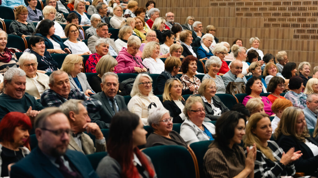 Słuchacze Uniwersytetu Trzeciego Wieku w Akademii Humanitas podczas inauguracji roku akademickiego – uśmiechnięta publiczność w auli.