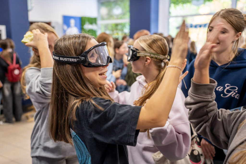 Grupa dziewcząt uczestniczy w wydarzeniu Girls Week w Akademii Humanitas. Mają założone alkogogle i uczestniczą w eksperymencie naukowym.
