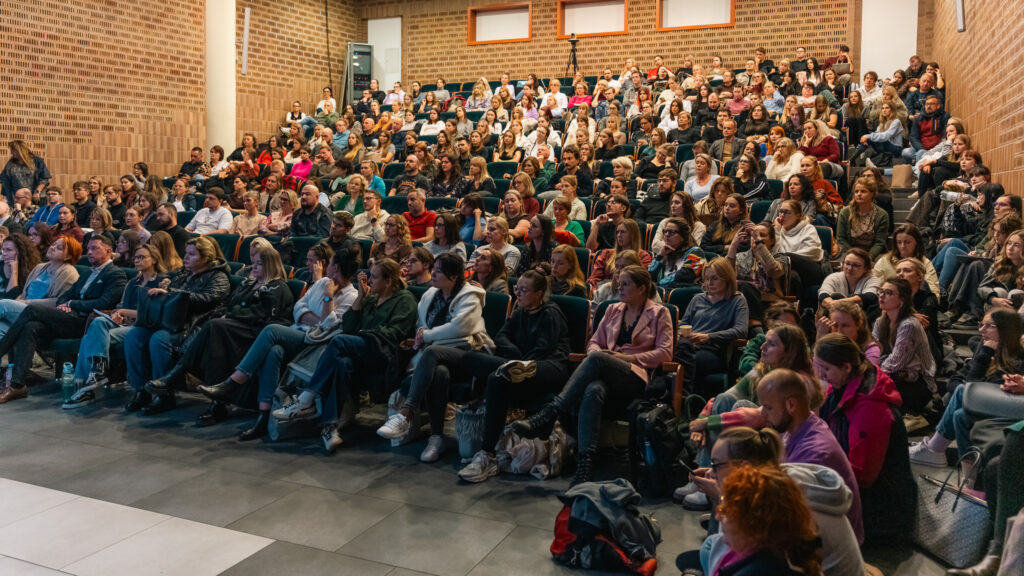 Pełna aula Akademii Humanitas podczas debaty, uczestnicy uważnie słuchają prelegentów.