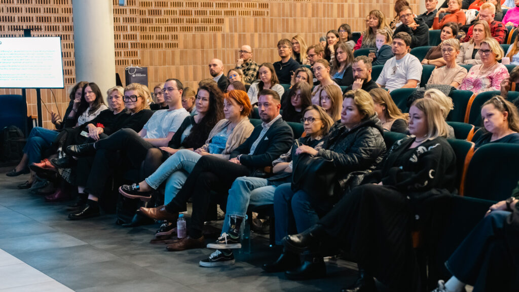 Pełna aula Akademii Humanitas podczas debaty, uczestnicy uważnie słuchają prelegentów.