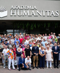Grupa seniorów pozuje do wspólnego zdjęcia przed budynkiem Akademii Humanitas.