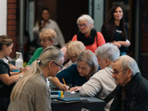 Seniorzy korzystają z badań profilaktycznych przy stolikach w Akademii Humanitas.
