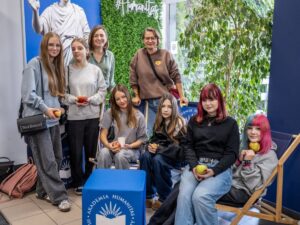 Grupa dziewcząt pozuje do zdjęcia na tle logotypu Akademii Humanitas.
