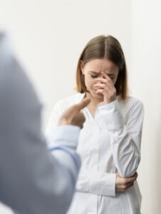 Zestresowana kobieta reagująca na krzyk lub oskarżenia w miejscu pracy.