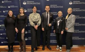 Grupa sześciu osób pozuje wspólnie do zdjęcia na tle granatowej ścianki z logo Akademii Humanitas.