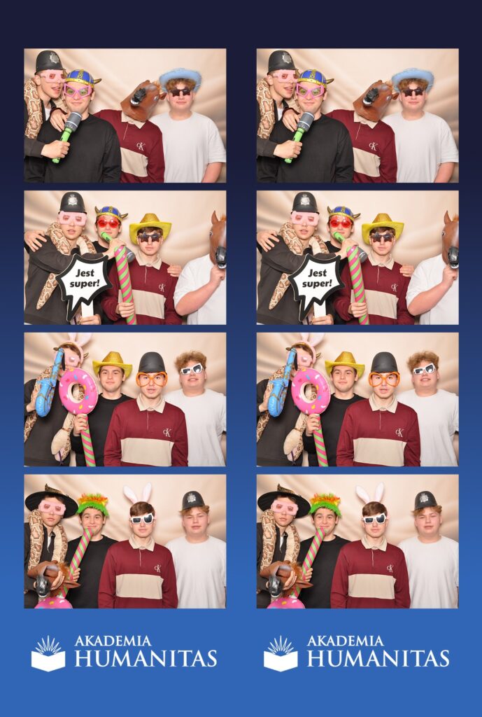 Zdjęcie z fotobudki przedstawiających czterech młodych mężczyzn pozujących w zabawnych przebraniach, okularach i maskach na tle beżowej scenografii, z logotypem Akademii Humanitas na dole.