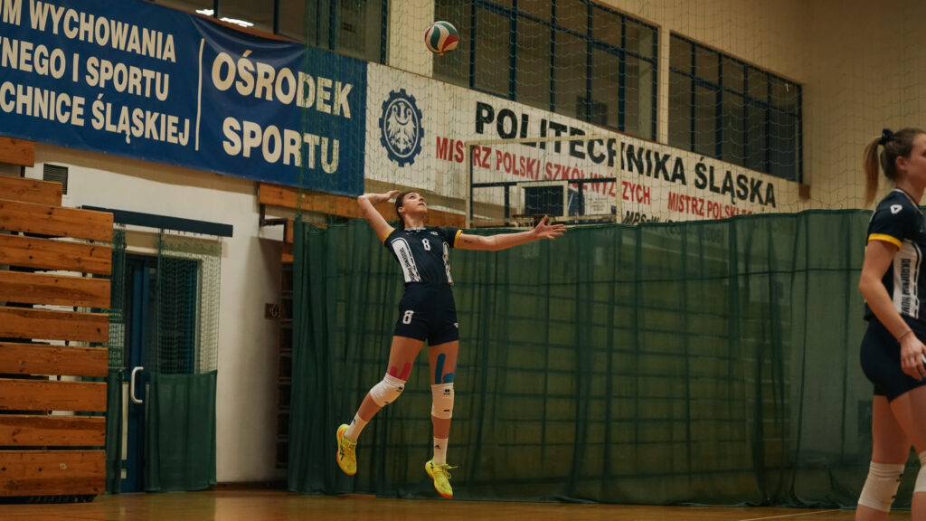 Zawodniczka AZS Humanitas Sosnowiec wykonuje wyrzut piłki przed serwisem podczas meczu siatkówki.
