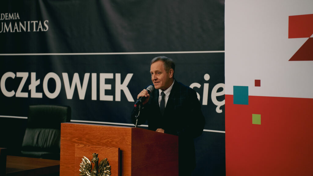 Mężczyzna przemawia przy mównicy z mikrofonem podczas wydarzenia w Akademii Humanitas; w tle baner z hasłem „Człowiek. To się liczy” oraz elementy graficzne Zagłębiowskiego Maratonu Nauki.
