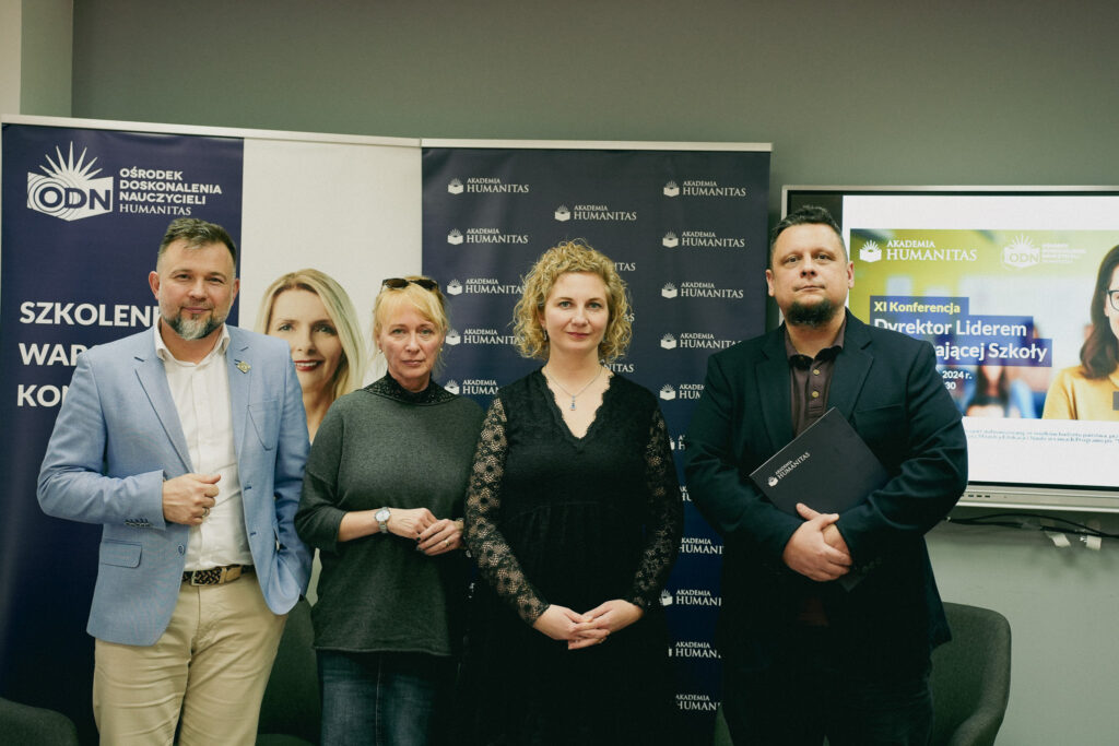 Cztery osoby stoją obok siebie i pozują do zdjęcia na tle banerów Akademii Humanitas oraz ekranu z informacją o konferencji.