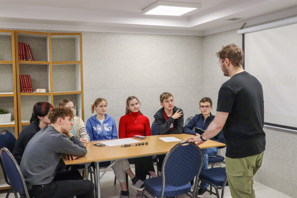 Prowadzący omawia zadanie z grupą uczniów podczas warsztatów edukacyjnych. 