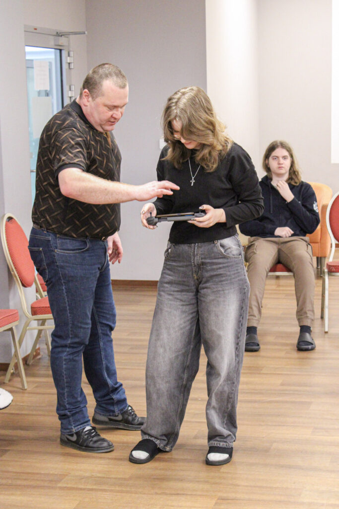 Prowadzący pomaga uczennicy w obsłudze urządzenia podczas praktycznych warsztatów edukacyjnych.
