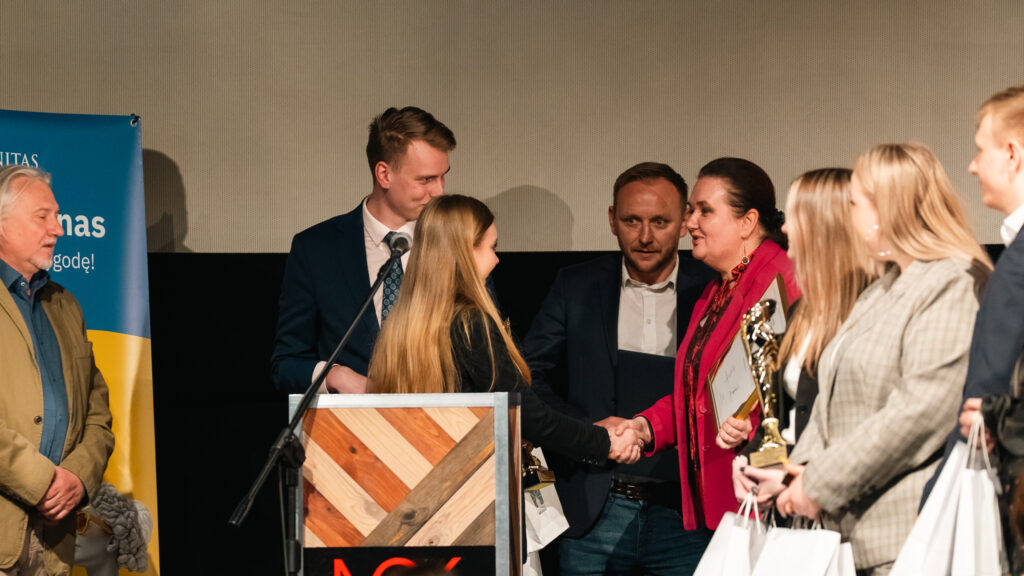 Wręczenie nagrody – uczestniczka ściska dłoń organizatorki, odbierając wyróżnienie i gratulacje.