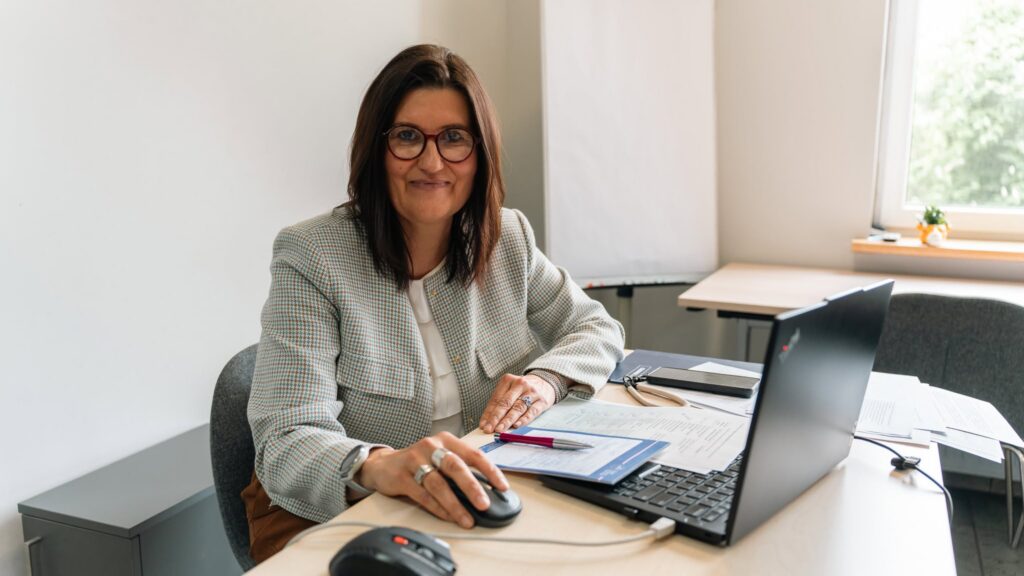 dr Joanna Miecznik-Warda – Przewodniczącej Komitetu Organizacyjnego, siedzi przy biurku z otwartym laptopem. 