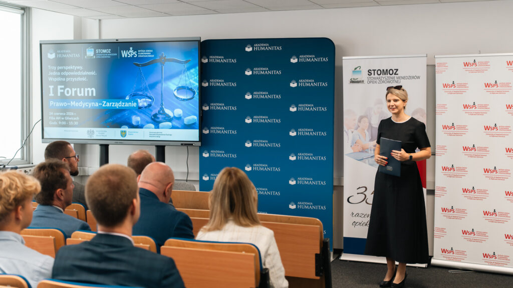 Prowadząca wydarzenia stoi na tle ścianki Akademii Humanitas oraz roll-upów STOMOZ oraz WSPS. Obok na ekranie slajd otwierający I Forum Prawo-Medycyna-Zarządanie.
