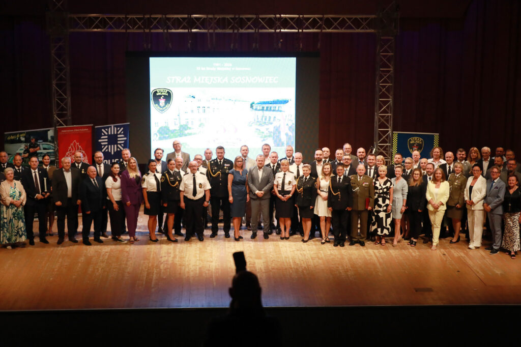 Uczestnicy jubileuszu 35-lecia Straży Miejskiej w Sosnowcu pozują do wspólnego zdjęcia na scenie.