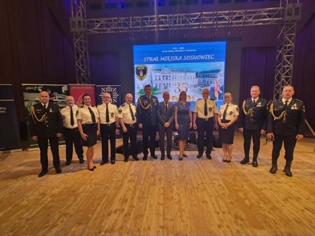 Uczestnicy jubileuszu 35-lecia Straży Miejskiej w Sosnowcu, w tym Rektor Akademii Humanitas, pozują do wspólnego zdjęcia na scenie.