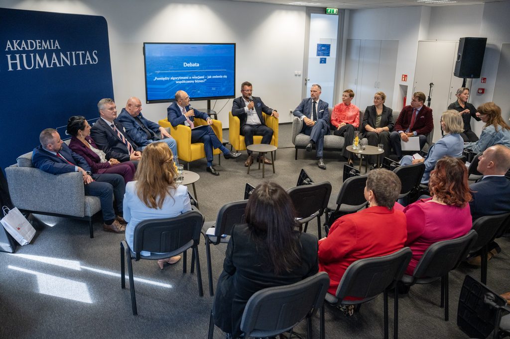Debata Akademii Humanitas z udziałem panelistów i publiczności. Uczestnicy siedzą w sali konferencyjnej, a na ekranie widoczny jest temat rozmowy dotyczący wpływu algorytmów i relacji na współczesny biznes.