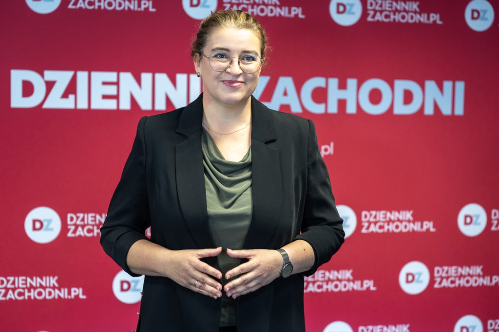 Przedstawicielka Akademii Humanitas pozuje na tle ścianki Dziennika Zachodniego. Zdjęcie wykonano podczas wydarzenia biznesowego z udziałem partnerów i uczestników kongresu.
