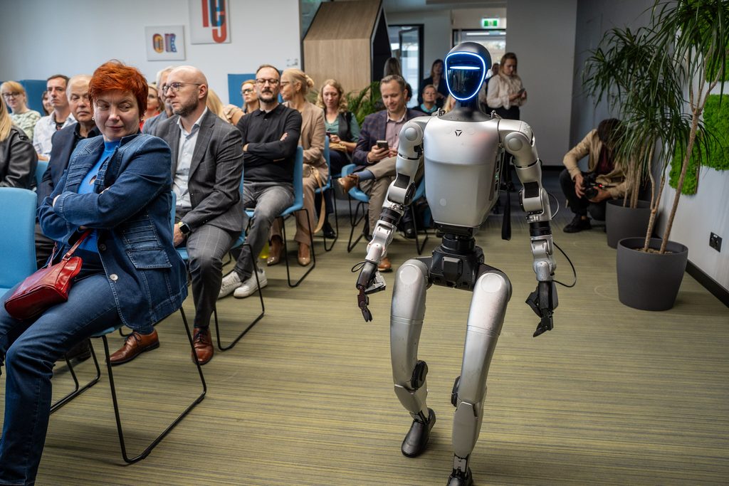 Humanoidalny robot z niebieskim podświetleniem twarzy stoi wśród uczestników X Jaworznickich Dni dla Biznesu.