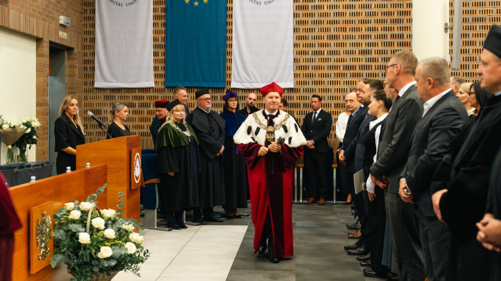 Rektor Akademii Humanitas w uroczystym stroju akademickim przechodzi przez aulę w asyście władz uczelni i zaproszonych gości podczas inauguracji roku akademickiego.