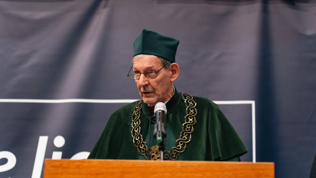 Założyciel i Kanclerz Akademii Humanitas Aleksander Dudek przemawia przy mównicy w zielonej todze akademickiej podczas jubileuszowej inauguracji roku akademickiego.