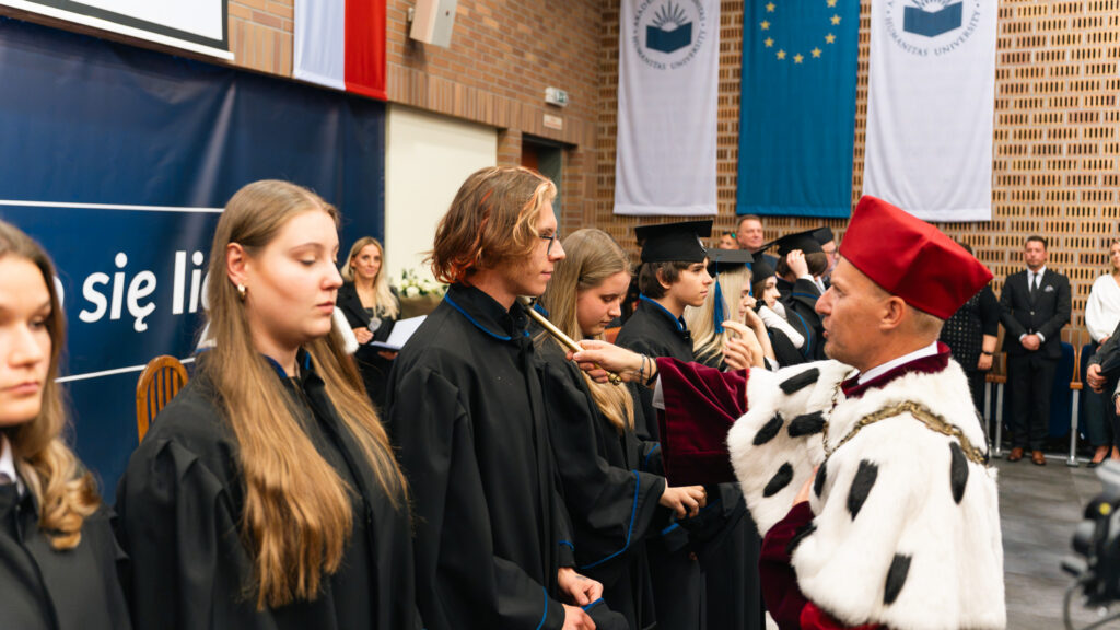 Rektor Akademii Humanitas dr Mariusz Lekston dokonuje uroczystej immatrykulacji studentów, dotykając ramienia studenta berłem rektorskim podczas inauguracji roku akademickiego.