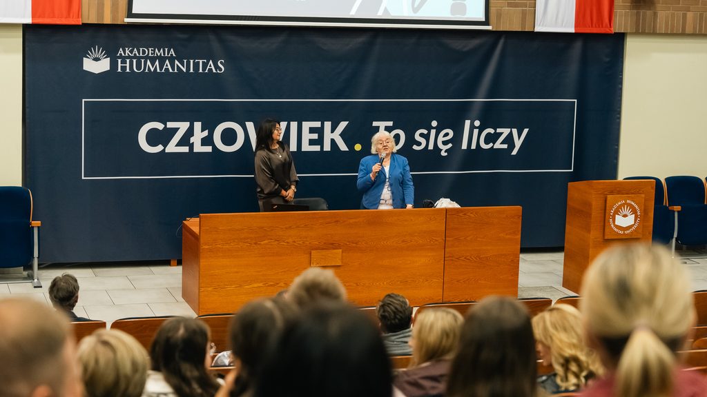 Prelegentka z mikrofonem występuje przed publicznością w auli Akademii Humanitas podczas konferencji „O zdrowiu, dla zdrowia”.