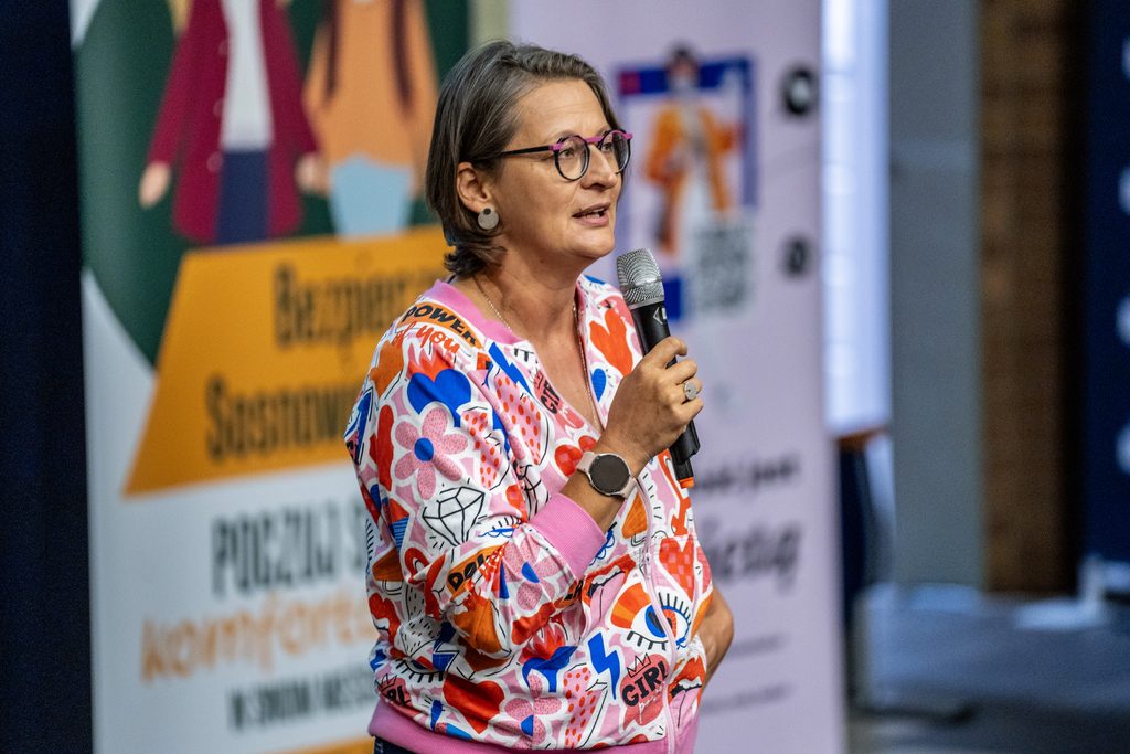 Prelegentka w kolorowej bluzie przemawia z mikrofonem podczas wydarzenia Girls’ Week.