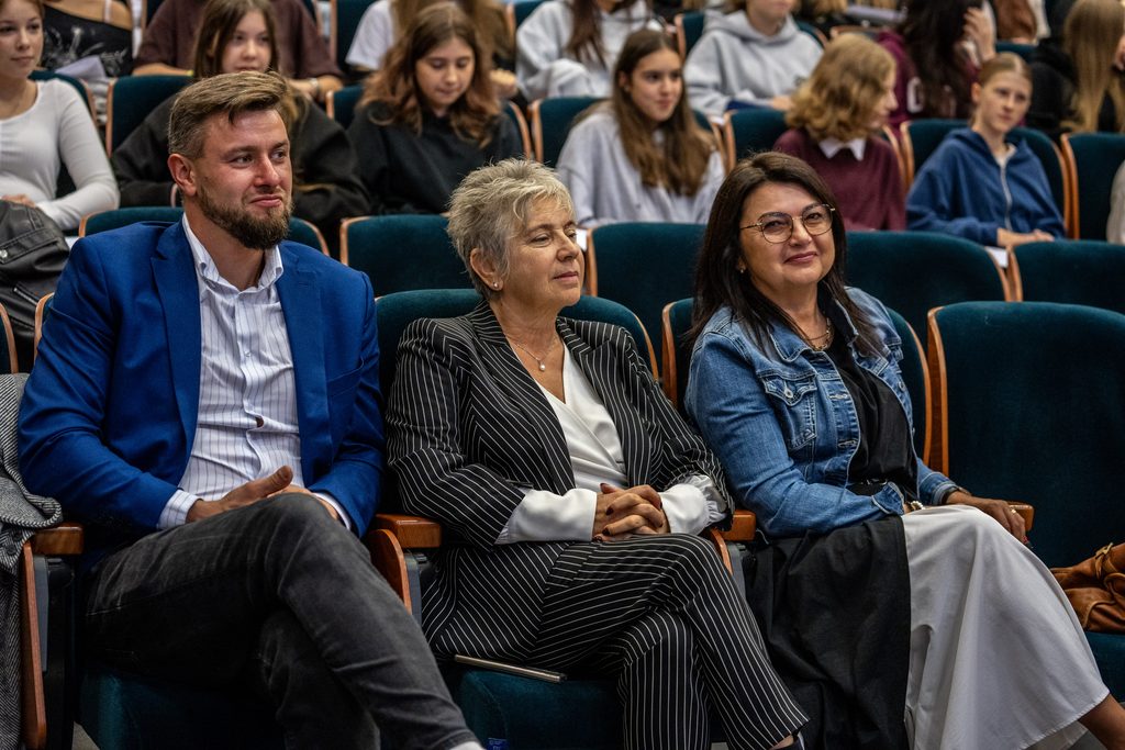 Uczestnicy i prelegenci siedzą w auli podczas Girls’ Week w Akademii Humanitas, w tle widoczna młodzież.