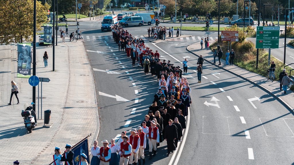 Uroczysty orszak akademicki przechodzi ulicą w Katowicach w asyście służb i orkiestry.