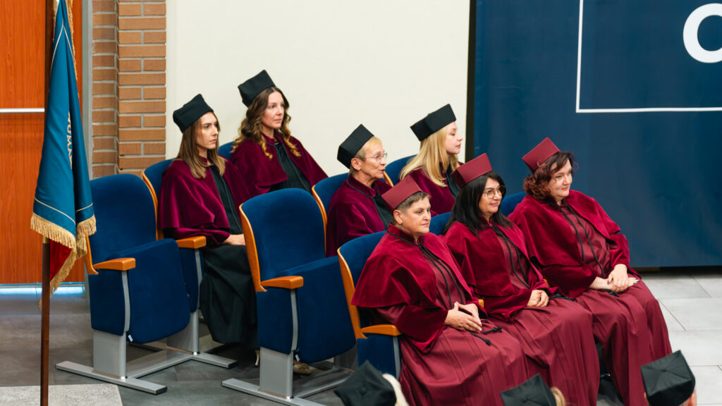 Członkinie Senatu Akademii Humanitas w bordowych togach i biretach akademickich siedzą w auli podczas uroczystej inauguracji roku akademickiego 2026/2027.