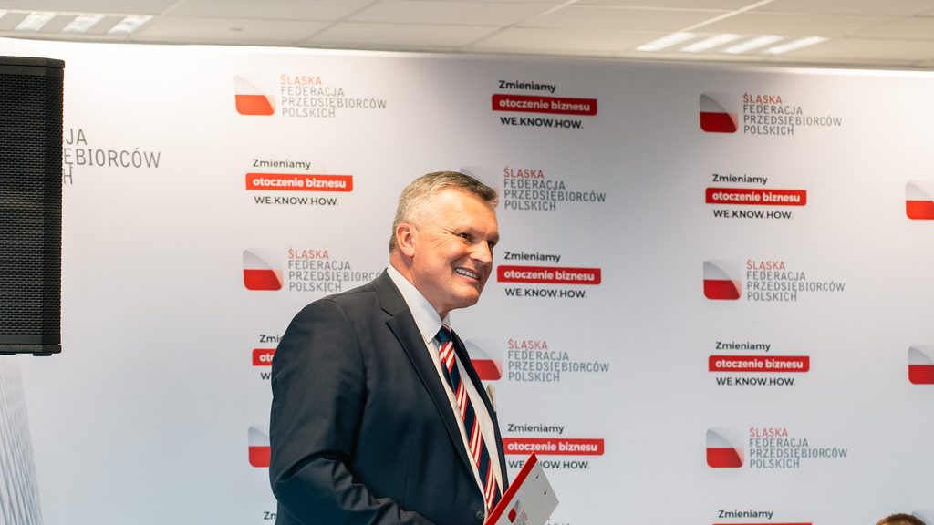 Uczestnik wydarzenia pozuje do zdjęcia na tle ścianki Śląskiej Federacji Przedsiębiorców Polskich.