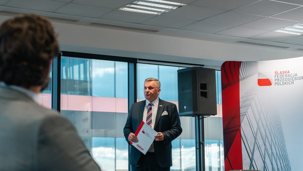 Uczestnik spotkania zabiera głos podczas wystąpienia na tle ścianki Śląskiej Federacji Przedsiębiorców Polskich.