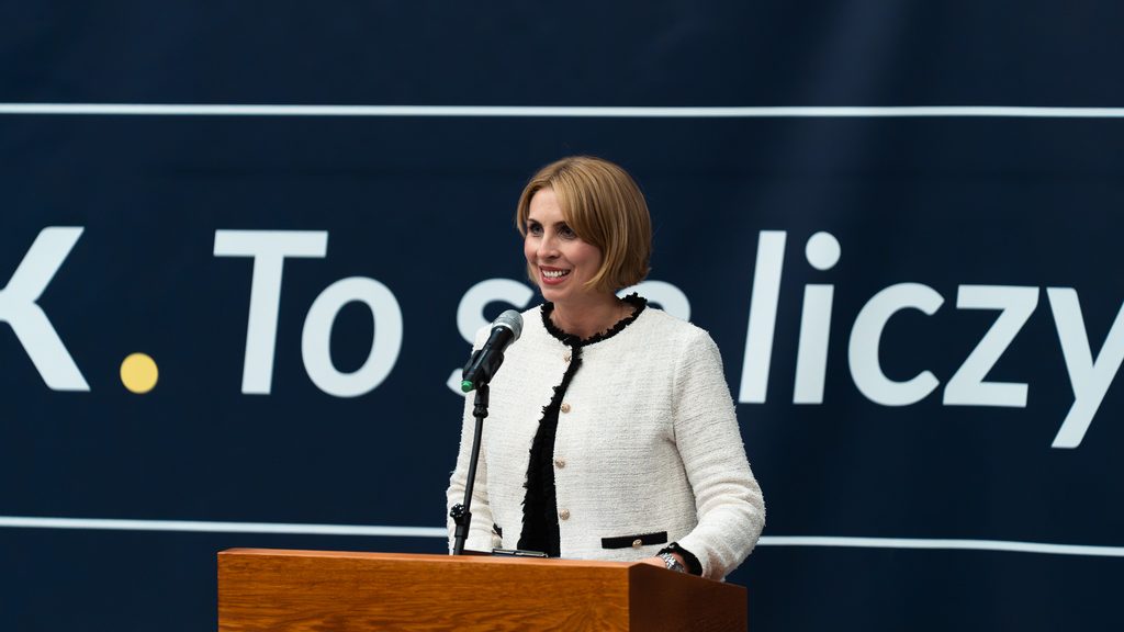 Kobieta w białym żakiecie z czarnymi wykończeniami przemawia przy mikrofonie za mównicą Akademii Humanitas.