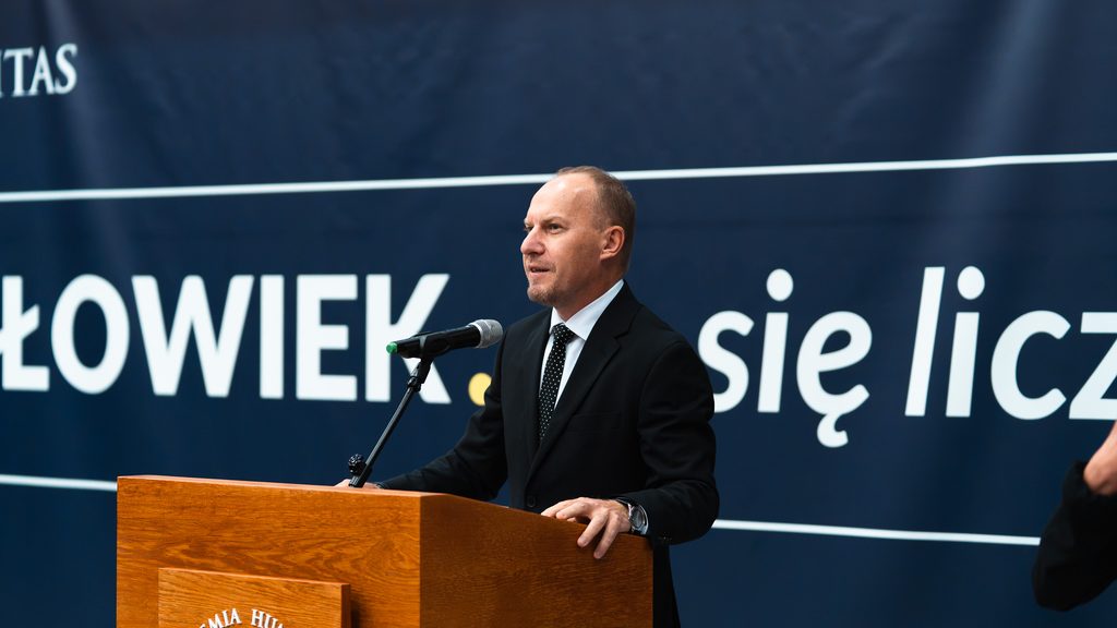 Rektor, dr MAriusz Lekston, przemawia przy mównicy Akademii Humanitas na tle granatowej ścianki z hasłem „Człowiek. To się liczy”.