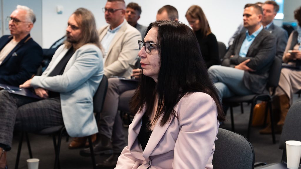 Uczestnicy szkolenia z cyberbezpieczeństwa słuchają wystąpienia eksperta w sali konferencyjnej.