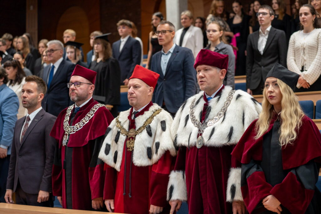 Przedstawiciele władz uczelni w uroczystych togach akademickich podczas inauguracji roku akademickiego 2026/2027 w Rybniku. W tle zgromadzeni uczestnicy wydarzenia.