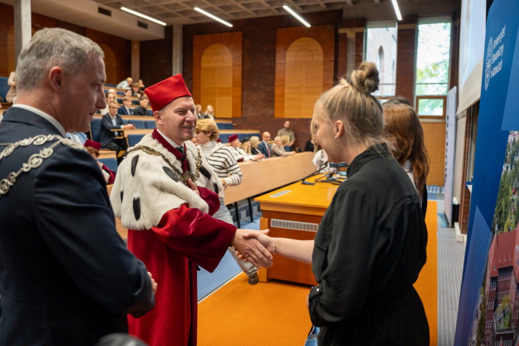 Rektor Akademii Humanitas dr Mariusz Lekston gratuluje studentce podczas uroczystej immatrykulacji w Rybniku, podając jej rękę.